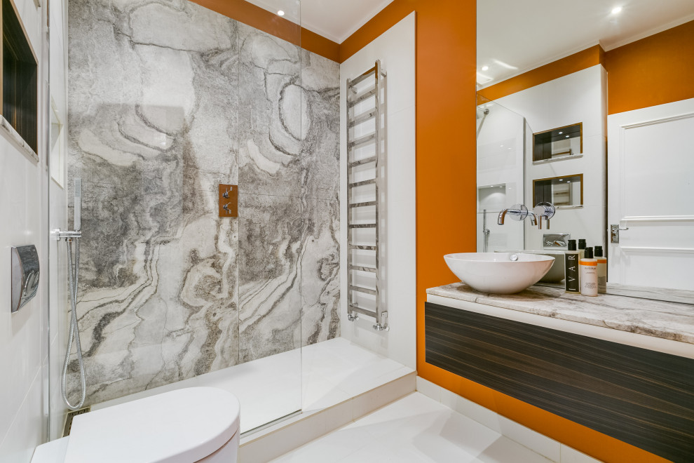 Inspiration for a mid-sized contemporary 3/4 bathroom in London with flat-panel cabinets, dark wood cabinets, an alcove shower, a wall-mount toilet, gray tile, porcelain tile, orange walls, porcelain floors, a vessel sink, white floor and grey benchtops.
