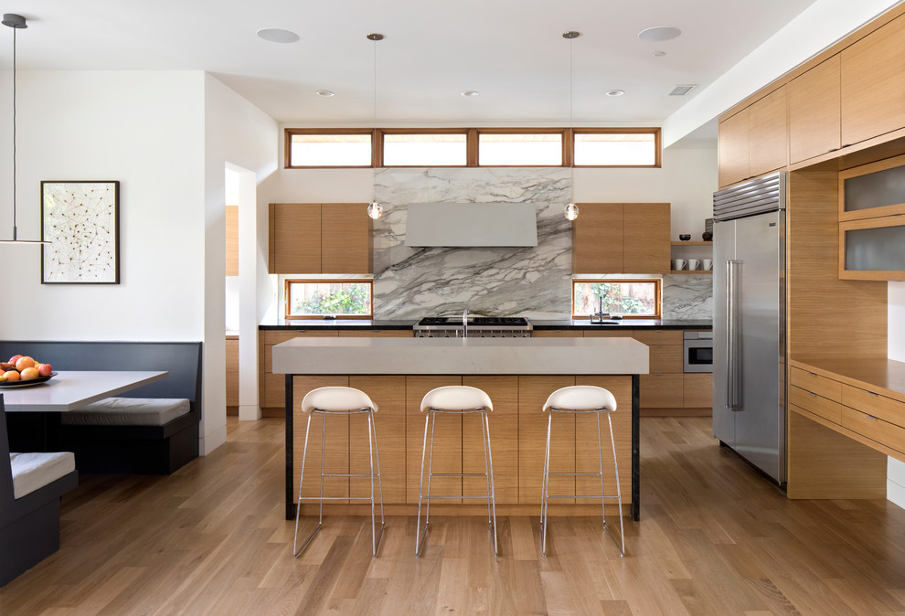 Contemporary eat-in kitchen in San Francisco with flat-panel cabinets, light wood cabinets, multi-coloured splashback, marble splashback, stainless steel appliances, light hardwood floors, with island and beige floor.