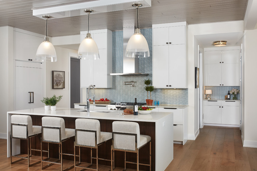 Large contemporary l-shaped open plan kitchen in Grand Rapids with an undermount sink, flat-panel cabinets, white cabinets, solid surface benchtops, blue splashback, medium hardwood floors, with island, panelled appliances, ceramic splashback, brown floor and white benchtop.