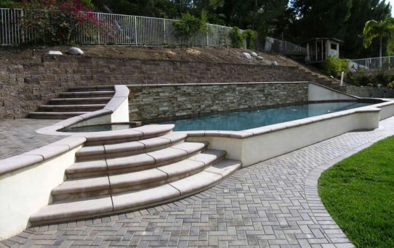 This is an example of a mid-sized traditional backyard rectangular lap pool in Orange County with brick pavers.