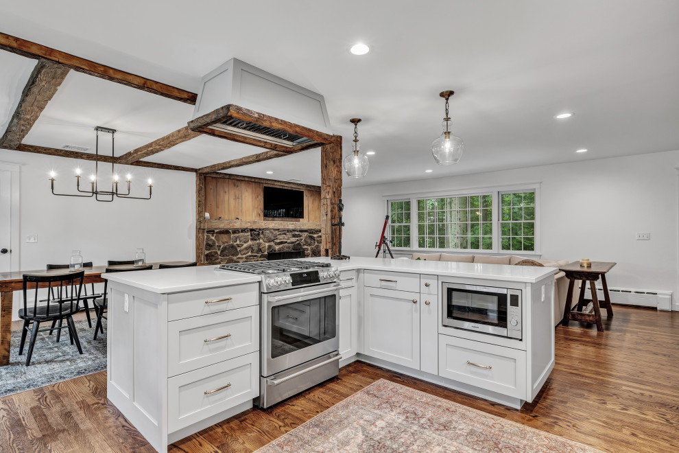 Large country u-shaped medium tone wood floor, brown floor and exposed beam eat-in kitchen photo in New York with a farmhouse sink, shaker cabinets, gray cabinets, quartz countertops, white backsplash, subway tile backsplash, stainless steel appliances, an island and white countertops