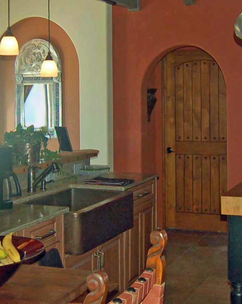 This is an example of a mid-sized mediterranean u-shaped open plan kitchen in San Luis Obispo with a farmhouse sink, raised-panel cabinets, distressed cabinets, solid surface benchtops, panelled appliances, cement tiles, multiple islands, beige floor, green benchtop and exposed beam.