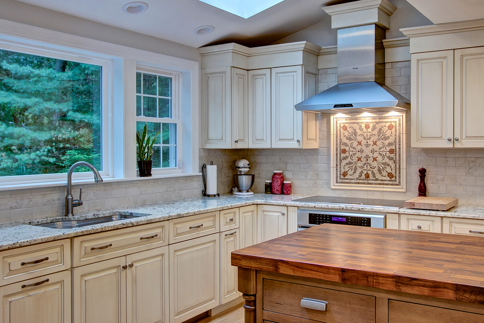 Inspiration for a large transitional u-shaped light wood floor eat-in kitchen remodel in Boston with an undermount sink, raised-panel cabinets, distressed cabinets, granite countertops, beige backsplash, porcelain backsplash, stainless steel appliances and two islands