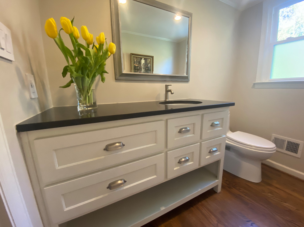 This is an example of a mid-sized country bathroom in Atlanta with white cabinets, medium hardwood floors, an undermount sink, granite benchtops, multi-coloured floor, black benchtops, a niche, a single vanity and a freestanding vanity.