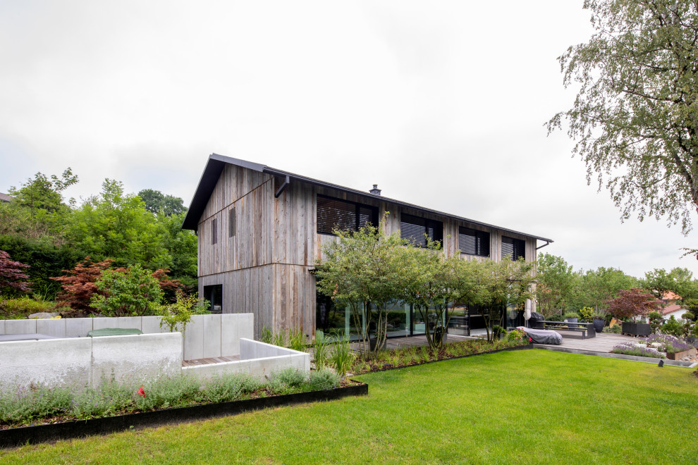 Großes, Zweistöckiges Modernes Haus mit grauer Fassadenfarbe, Satteldach, Ziegeldach, grauem Dach und Verschalung in München
