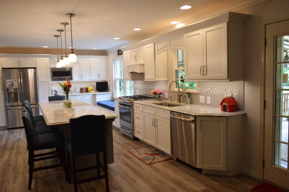 Kitchen - huge transitional medium tone wood floor and brown floor kitchen idea with an undermount sink, shaker cabinets, white cabinets, quartz countertops, gray backsplash, subway tile backsplash, stainless steel appliances and an island