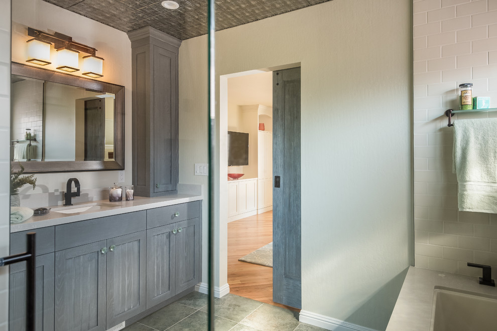 This is an example of a large transitional master wet room bathroom in San Francisco with shaker cabinets, blue cabinets, an undermount tub, a two-piece toilet, green tile, slate, white walls, porcelain floors, an undermount sink, engineered quartz benchtops, green floor and a hinged shower door.