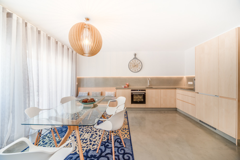 This is an example of a contemporary l-shaped eat-in kitchen in Other with an undermount sink, flat-panel cabinets, beige cabinets, concrete benchtops, grey splashback, black appliances, concrete floors, no island, grey floor and grey benchtop.