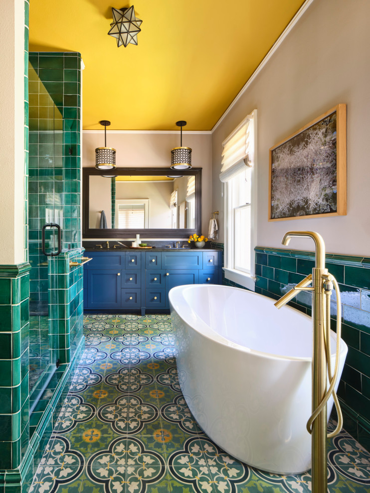 Classic ensuite bathroom in Other with shaker cabinets, blue cabinets, a freestanding bath, cement flooring, a submerged sink, green floors, a hinged door, double sinks, a built in vanity unit, an alcove shower, green tiles, grey walls, black worktops and metro tiles.
