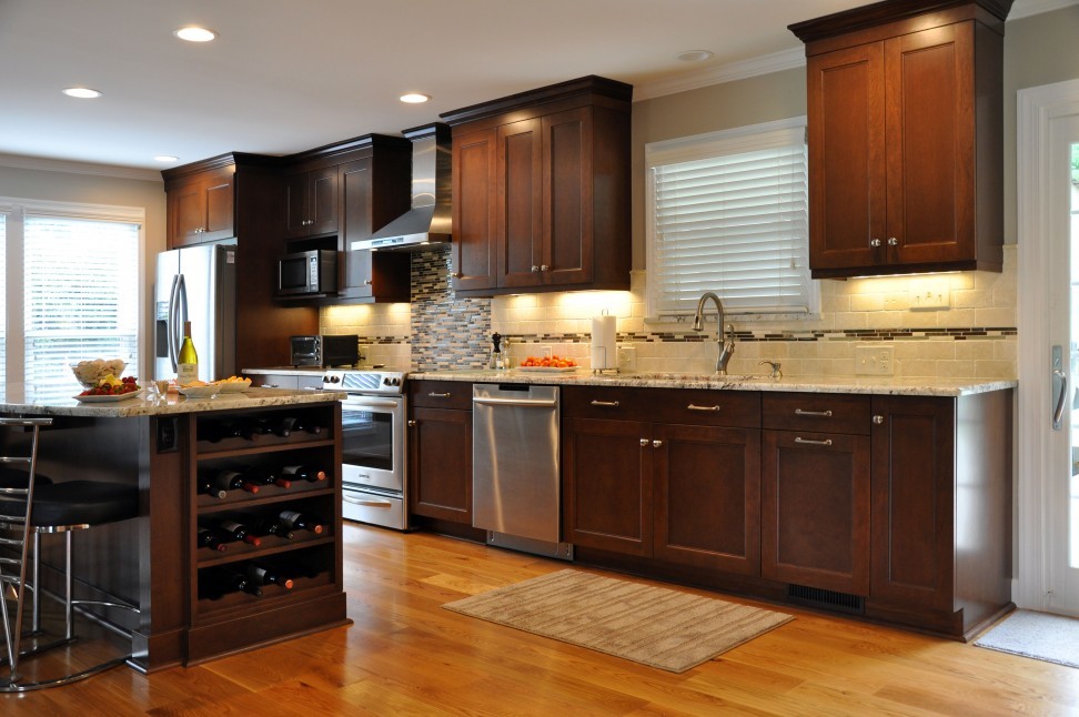 Large transitional single-wall medium tone wood floor eat-in kitchen photo in Houston with an undermount sink, recessed-panel cabinets, dark wood cabinets, multicolored backsplash, stainless steel appliances, beige walls and an island