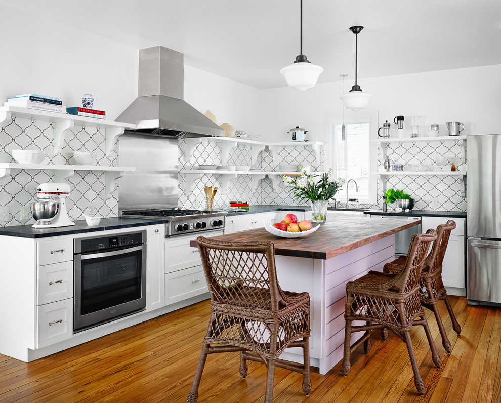 Inspiration for a beach style l-shaped kitchen in Austin with a farmhouse sink, open cabinets, white cabinets, soapstone benchtops, white splashback, ceramic splashback, stainless steel appliances, medium hardwood floors and with island.