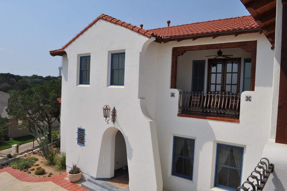 This is an example of a large two-storey stucco white exterior in Austin with a hip roof.