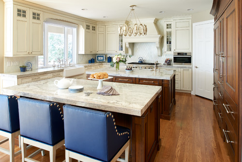 Bright, modern kitchen with white shaker kitchen cabinets in Mississauga, large marble-look island, blue bar stools, and warm wood flooring.