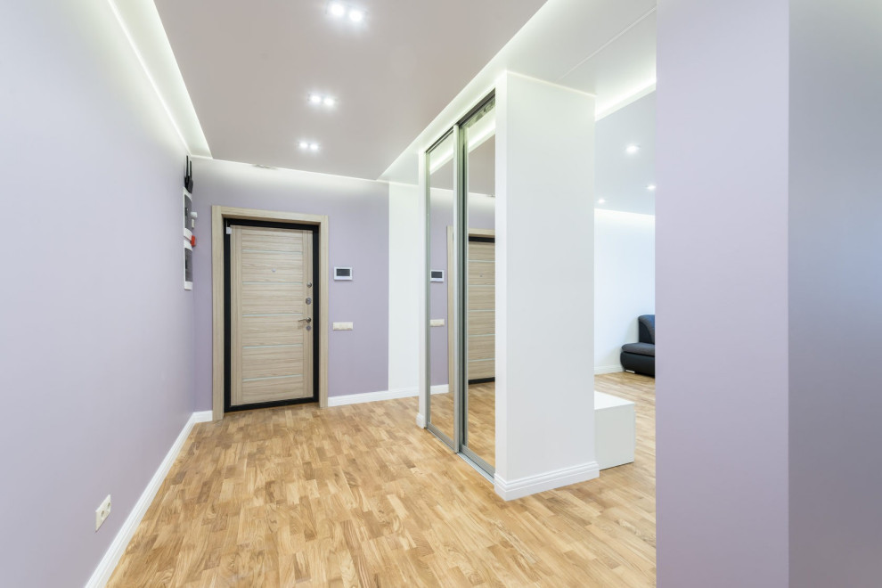 Photo of a mid-sized contemporary foyer in Other with beige floor, purple walls, laminate floors, a single front door and a light wood front door.