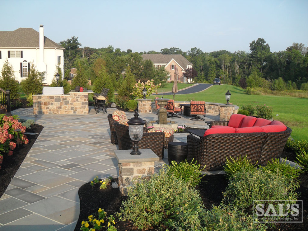 Inspiration for a large traditional backyard patio in Philadelphia with natural stone pavers.