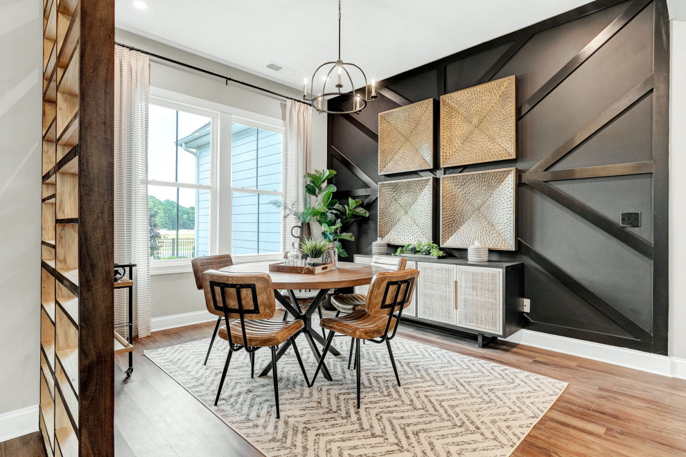 Idée de décoration pour une salle à manger ouverte sur la cuisine design avec un mur noir, parquet clair, un sol marron et du lambris.