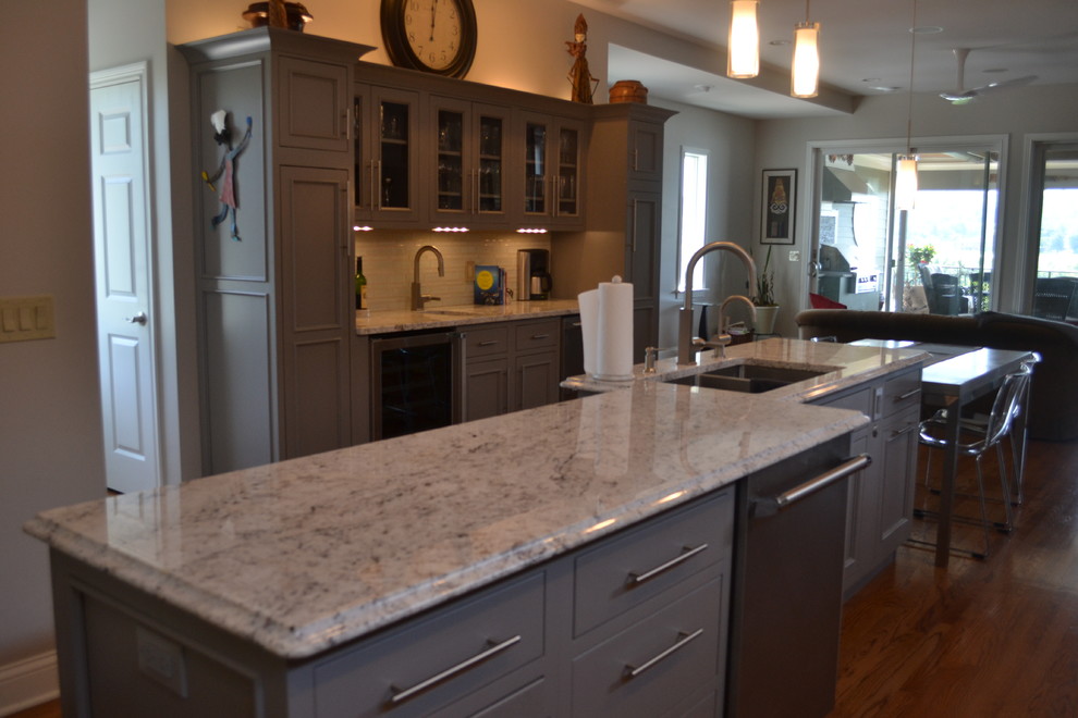 Inspiration for a large transitional l-shaped medium tone wood floor open concept kitchen remodel in Cincinnati with an undermount sink, gray cabinets, granite countertops, multicolored backsplash, mosaic tile backsplash, stainless steel appliances, an island and beaded inset cabinets