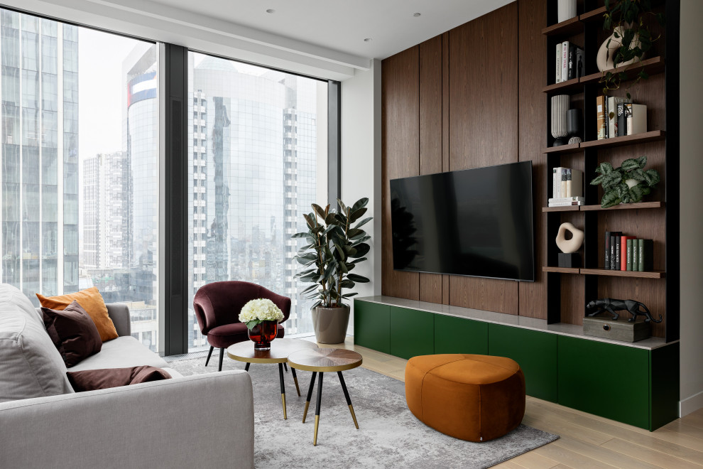 Cette photo montre une salle de séjour tendance de taille moyenne avec un mur beige, un sol en bois brun, un téléviseur fixé au mur et un sol beige.