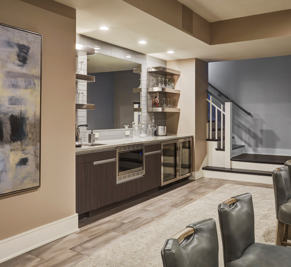 Design ideas for a large contemporary single-wall wet bar in Chicago with an undermount sink, flat-panel cabinets, dark wood cabinets, granite benchtops, white splashback, ceramic splashback, laminate floors, brown floor and white benchtop.