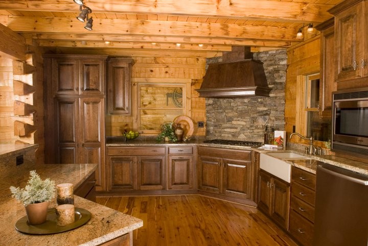 Example of a mid-sized mountain style l-shaped dark wood floor and brown floor enclosed kitchen design in Raleigh with stainless steel appliances, dark wood cabinets, a farmhouse sink, raised-panel cabinets, granite countertops, gray backsplash, stone tile backsplash, a peninsula and brown countertops