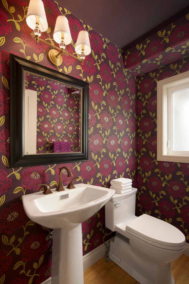 Photo of a small traditional powder room in Calgary with a two-piece toilet, red walls, light hardwood floors, an integrated sink and brown floor.