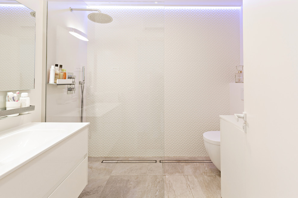 This is an example of a contemporary bathroom in Other with a curbless shower, a wall-mount toilet, white tile, a trough sink and beige floor.