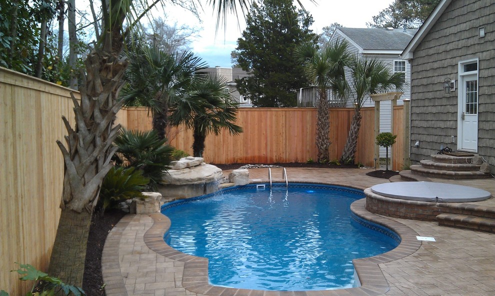 Inspiration for a small traditional backyard custom-shaped natural pool in Other with a water feature and brick pavers.