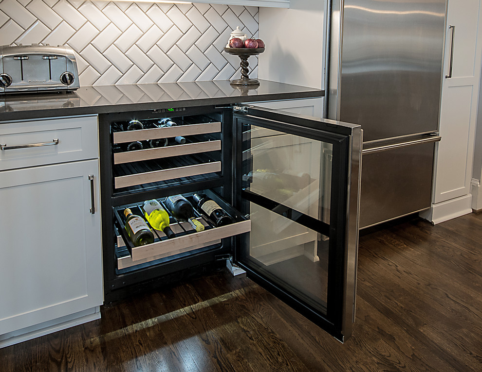 Inspiration for a large transitional l-shaped medium tone wood floor and brown floor open concept kitchen remodel in Atlanta with a farmhouse sink, shaker cabinets, white cabinets, quartzite countertops, white backsplash, subway tile backsplash, stainless steel appliances and an island