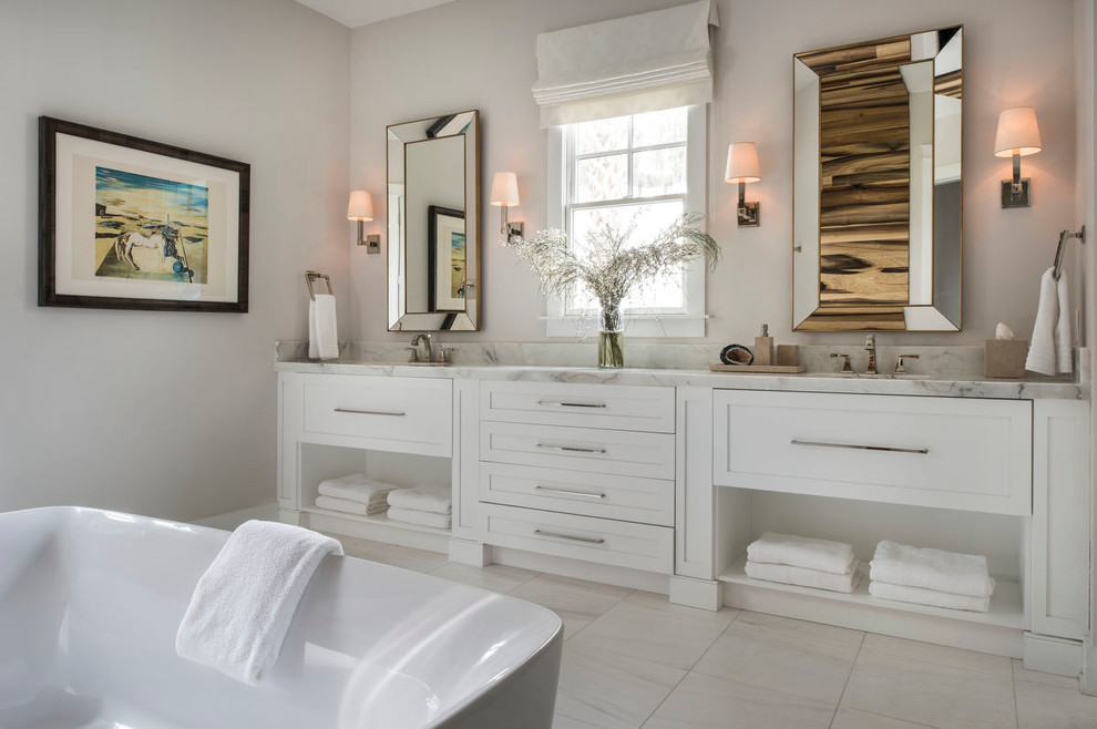 Photo of a large country master bathroom in Orlando with furniture-like cabinets, white cabinets, a freestanding tub, a curbless shower, white tile, stone slab, beige walls, marble floors, an undermount sink and marble benchtops.