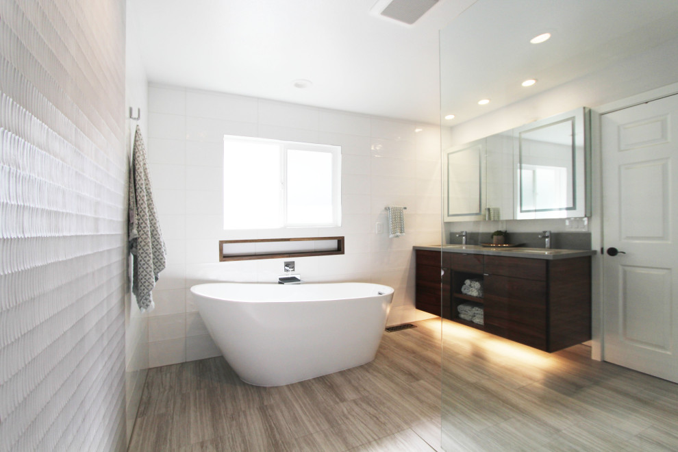 Freestanding bathtub - large transitional master white tile and ceramic tile porcelain tile, gray floor and double-sink freestanding bathtub idea with flat-panel cabinets, dark wood cabinets, a one-piece toilet, white walls, an undermount sink, quartz countertops, gray countertops, a niche and a floating vanity