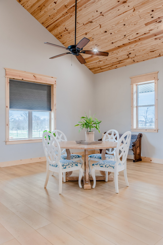 Immagine di una sala da pranzo aperta verso il soggiorno country di medie dimensioni con pareti bianche, pavimento in vinile, pavimento beige, soffitto in legno e pareti in perlinato