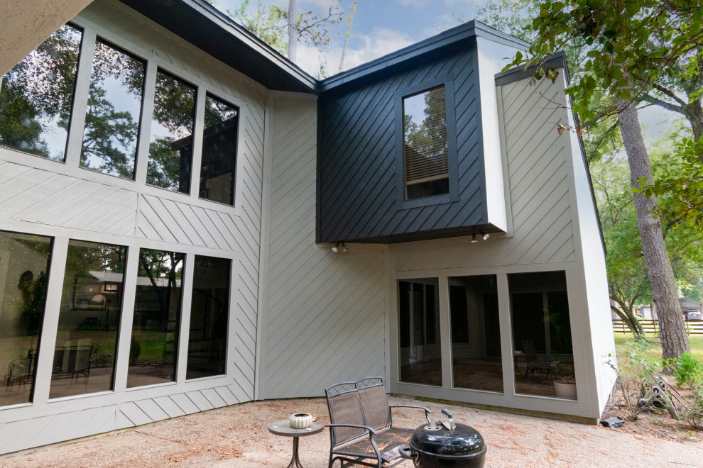 Cette image montre une très grande façade de maison grise design en panneau de béton fibré et bardage à clin à un étage avec un toit à deux pans, un toit en shingle et un toit noir.