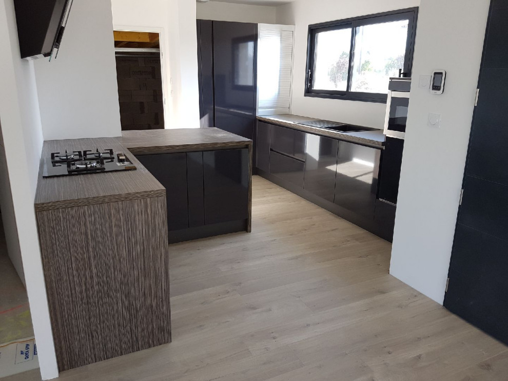 Mid-sized modern l-shaped open plan kitchen in Toulouse with a single-bowl sink, beaded inset cabinets, grey cabinets, wood benchtops, panelled appliances, a peninsula and beige benchtop.