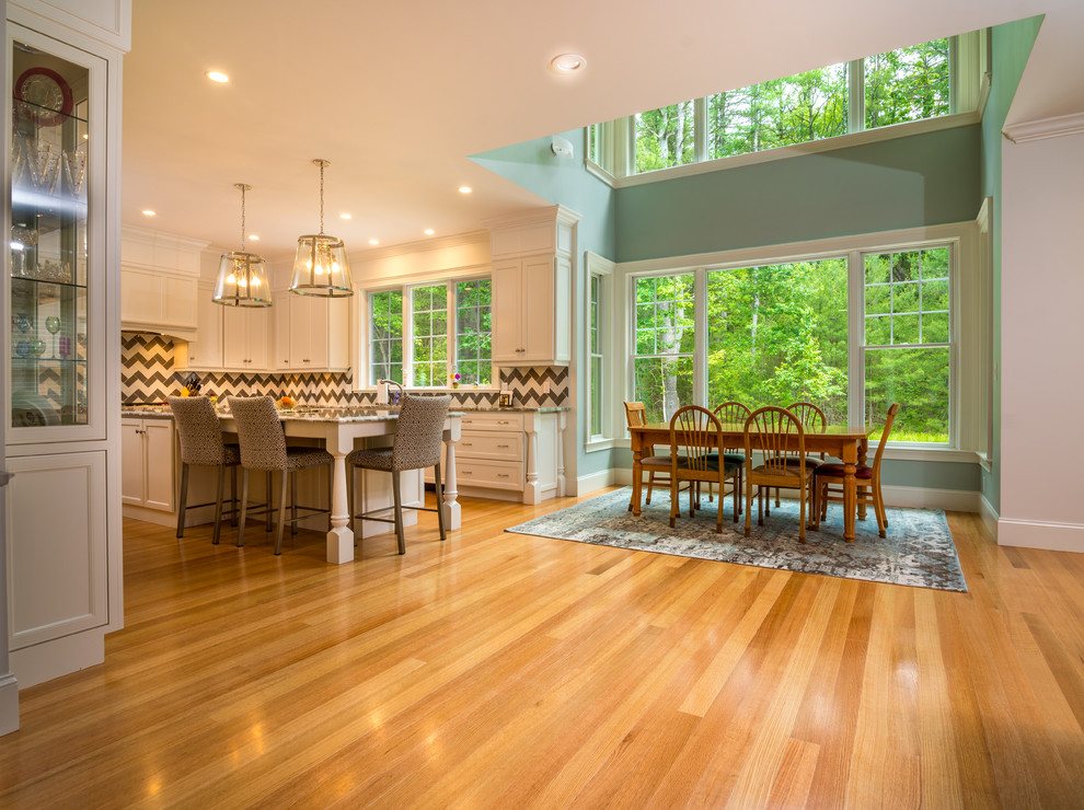 This is an example of a large transitional u-shaped open plan kitchen in Boston with recessed-panel cabinets, white cabinets, granite benchtops, grey splashback, ceramic splashback, stainless steel appliances, medium hardwood floors and with island.