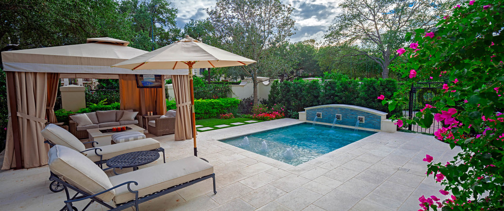 Small traditional front yard rectangular pool in Houston with a water feature and natural stone pavers.