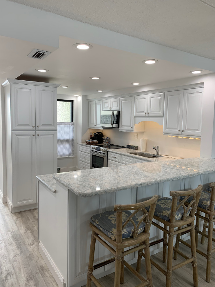 Eat-in kitchen - small transitional l-shaped laminate floor and gray floor eat-in kitchen idea in Philadelphia with an undermount sink, raised-panel cabinets, white cabinets, granite countertops, stainless steel appliances, a peninsula and gray countertops