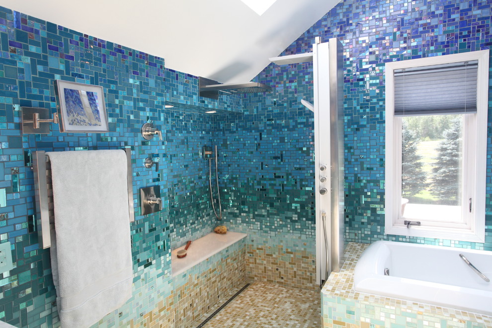 Photo of a large tropical master bathroom in New York with flat-panel cabinets, black cabinets, a drop-in tub, an open shower, a one-piece toilet, blue tile, glass tile, blue walls, ceramic floors, a pedestal sink, solid surface benchtops, beige floor and an open shower.