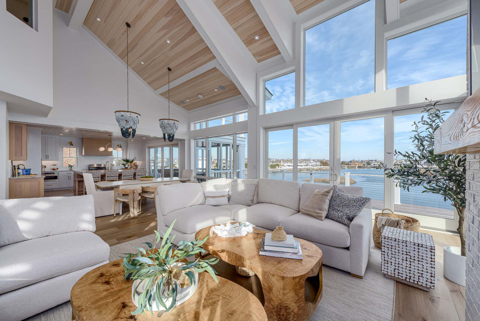 Inspiration for a beach style open concept living room in Philadelphia with white walls, light hardwood floors, brown floor and wood.