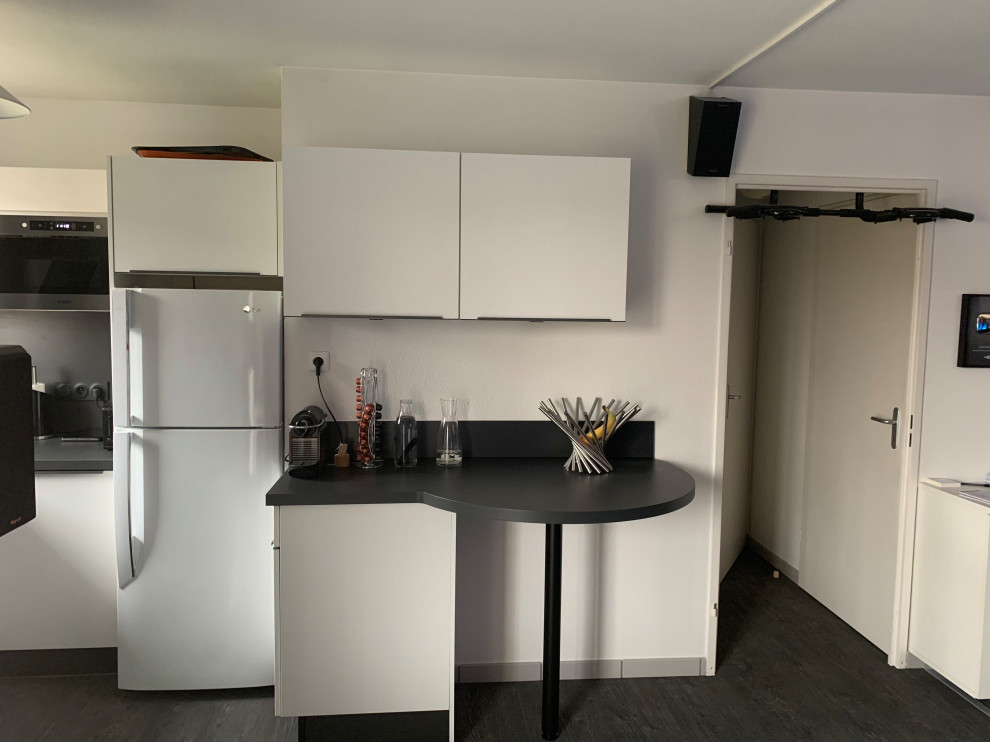 This is an example of a small modern l-shaped open plan kitchen in Toulouse with a single-bowl sink, laminate benchtops, grey splashback, black appliances, ceramic floors, white floor and grey benchtop.