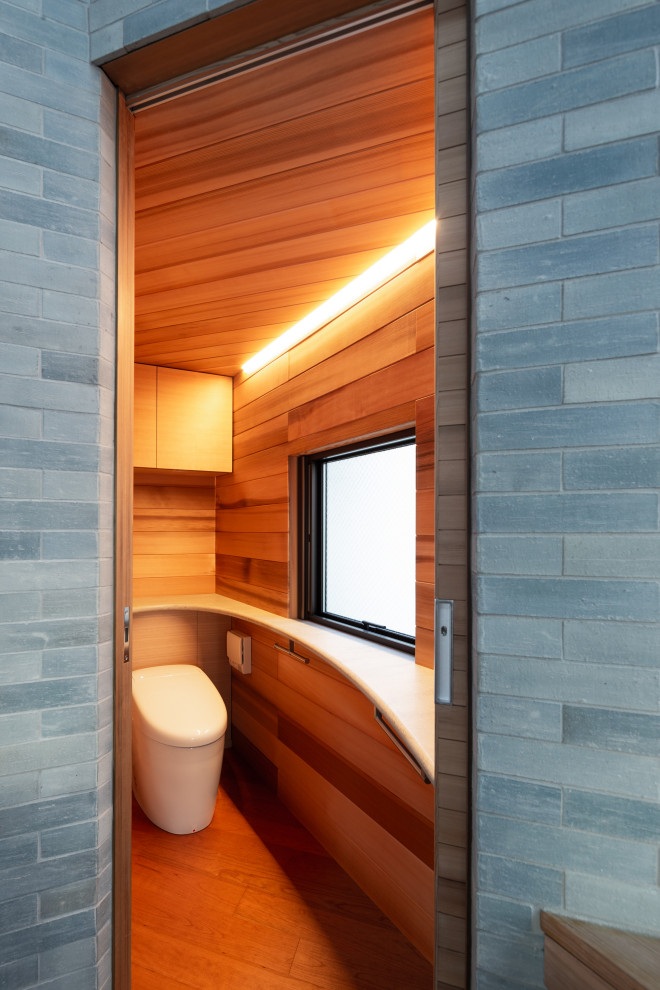 Idéer för att renovera ett mellanstort nordiskt grön grönt toalett, med luckor med profilerade fronter, skåp i mellenmörkt trä, en toalettstol med separat cisternkåpa, brun kakel, bruna väggar, mellanmörkt trägolv, ett integrerad handfat, träbänkskiva och brunt golv