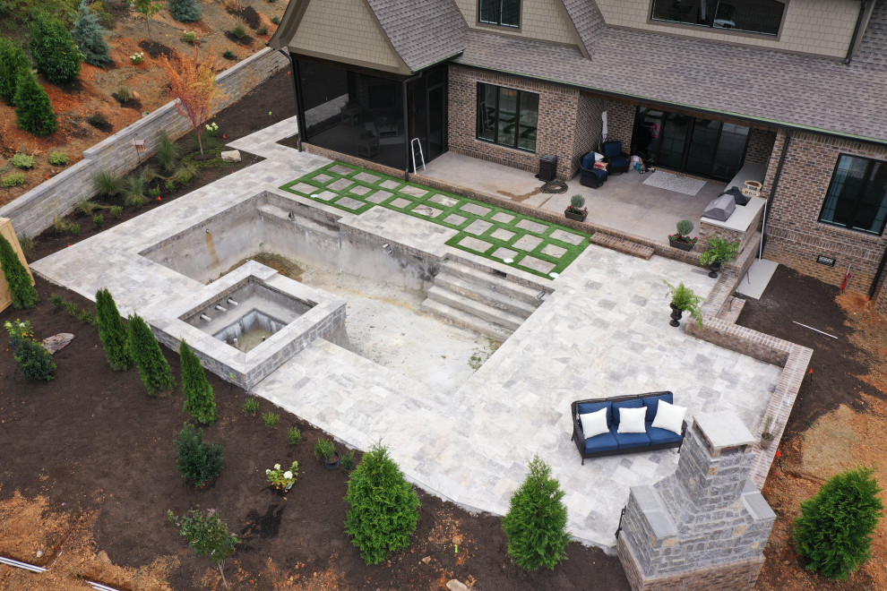 Exempel på en stor 60 tals anpassad pool på baksidan av huset, med naturstensplattor