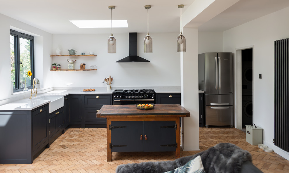 Small traditional open plan kitchen in London with shaker cabinets, dark wood cabinets, quartzite benchtops, medium hardwood floors and with island.