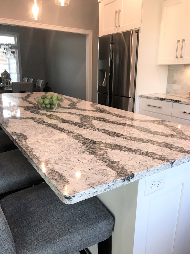Large transitional l-shaped medium tone wood floor and gray floor eat-in kitchen photo with an undermount sink, recessed-panel cabinets, white cabinets, quartz countertops, gray backsplash, marble backsplash, stainless steel appliances and an island