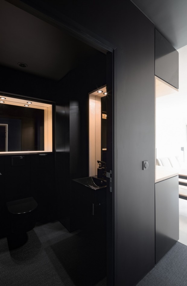 Inspiration for a mid-sized contemporary 3/4 bathroom in Paris with flat-panel cabinets, black cabinets, a corner shower, a wall-mount toilet, black walls, a console sink, solid surface benchtops, black floor, a hinged shower door and black benchtops.
