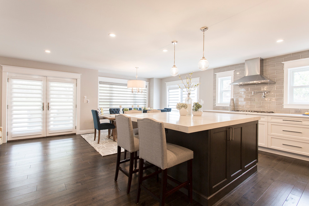 Inspiration for a large transitional l-shaped medium tone wood floor and brown floor eat-in kitchen remodel in Denver with a single-bowl sink, recessed-panel cabinets, white cabinets, quartz countertops, gray backsplash, ceramic backsplash, stainless steel appliances and two islands