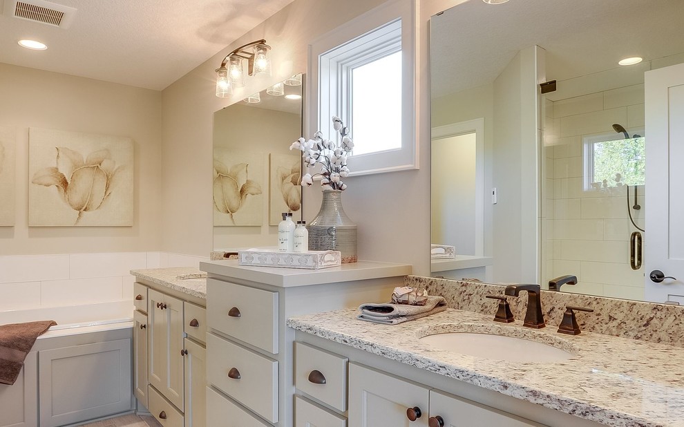 This is an example of a mid-sized transitional master bathroom in Minneapolis with beaded inset cabinets, grey cabinets, a drop-in tub, beige walls, porcelain floors, an undermount sink, granite benchtops, white floor and a hinged shower door.