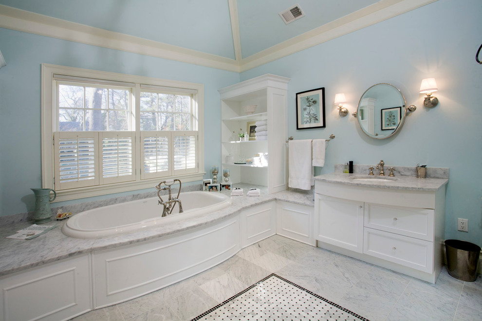 Photo of a large traditional master bathroom in New York with beaded inset cabinets, white cabinets, a drop-in tub, gray tile, stone slab, blue walls, marble floors, an undermount sink, marble benchtops and grey floor.