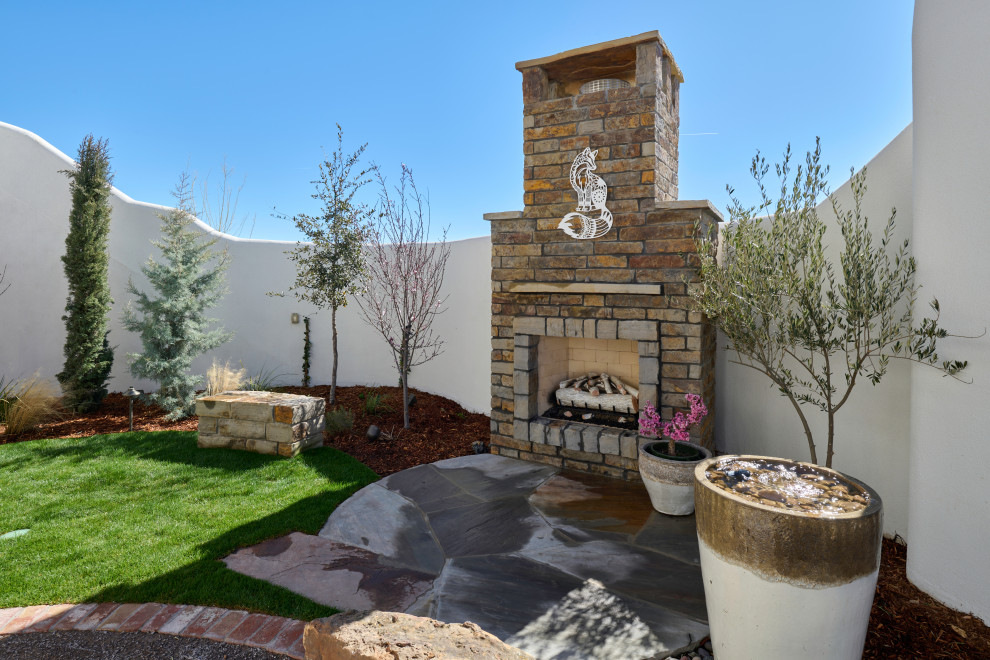 Imagen de patio ecléctico pequeño en patio con chimenea y adoquines de piedra natural