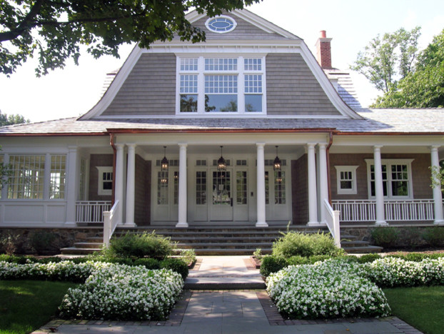 Inspiration for a large traditional two-storey beige house exterior in Chicago with mixed siding, a gambrel roof and a shingle roof.