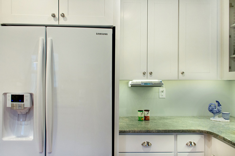 Example of a transitional l-shaped eat-in kitchen design with shaker cabinets, white cabinets, granite countertops and white appliances